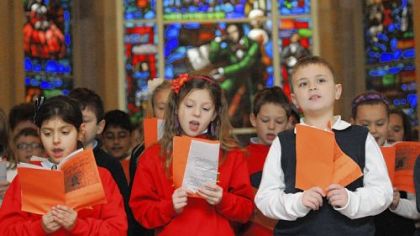 Leeann Parsi, Carlee Fettis and Mickey Gallagher, third-graders at St. Raphael School in Morningside, sing Friday at the memorial service honoring the 149th anniversary of Stephen Foster's death in the Temple of Memories at Allegheny Cemetery at Penn Avenue. The Stephen Foster Memorial Window is in the background.
