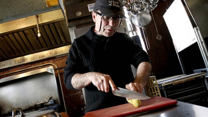 Toni Pais cuts into a squash in the kitchen at Cafe Zinho in Shadyside.
