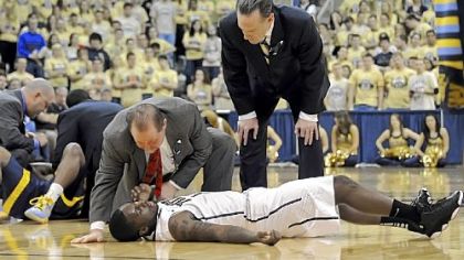 Pitt's Tray Woodall is attended to by trainer Tony Salesi and coach Jamie Dixon after colliding with Marquette's Derrick Wilson in the first half Saturday at Petersen Events Center.