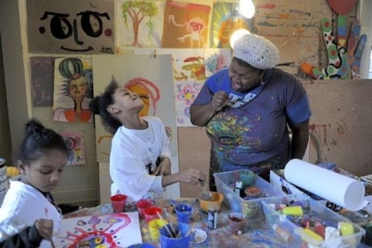 Trinity Reynolds, 6, left, paints while Tori Hammond, 8, center, laughs as artist Vanessa German sings at the Art House in Homewood.