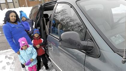 Shawntaye Sledge, left, holds her son Jason Taylor, 1, as she stands with the car that she won. Her son Justin Taylor, 4, right, and daughter Aubrey Taylor, 2, stand with her.