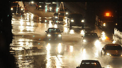 Cars and trucks in the "bathtub" area of the Parkway East dodge the water from the break.