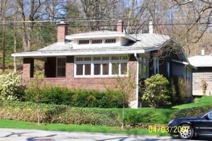Before photo shows how a previous owner of this Fox Chapel bungalow concealed a Craftsman-style dormer and exposed eaves and rafter tails with vinyl trim.