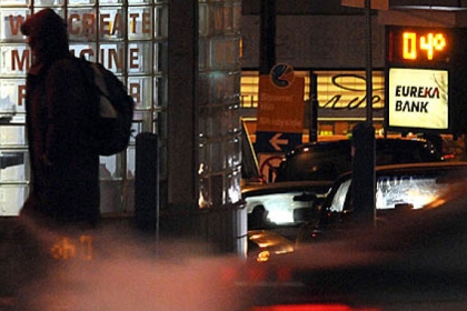 A pedestrain crosses McKee Place, Downtown, with 4 degrees showing before dawn on a nearby bank sign.
