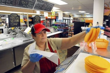 Becky Carl prepares a cheese order in the deli at Youngwood Corner Market. Ms. Carl starts before the store opens to prepare homemade soup and other hot foods.