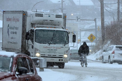 A cyclist rides through heavy snow and traffic on Banksville Road.