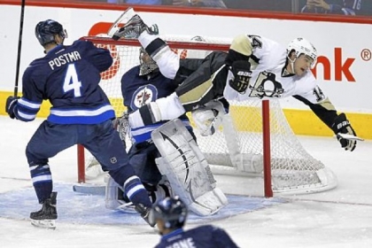Winnipeg Jets' Paul Postma sends Pittsburgh Penguins' Chris Kunitz flying in front of Jets goaltender Ondrej Pavelec during the first period.