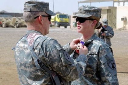 Col. Ricky Gibbs, an Army commander in Iraq, places a Purple Heart on the collar of Sgt. Jennifer Hunt, a civil affairs specialist, for wounds suffered in 2007 due to enemy contact during her deployment in support of Operation Iraqi Freedom.