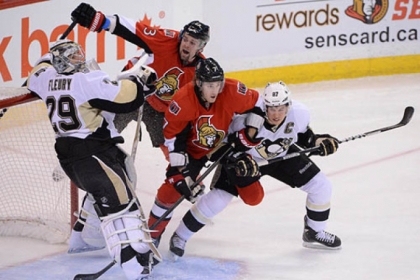 The Penguins' Sidney Crosby, right, ties up the Senators' Kyle Turris in front of Penguins goalie Marc-Andre Fleury as the Senators' Kaspars Daugavins, back, moves in.