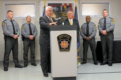 Gov. Tom Corbett, left at the podium Tuesday with Frank Noonan, commissioner of the state police, details his law enforcement budget and announces funding for three new classes of state police cadets. Behind the two are, at left, Troopers Greg Brown and Robert Klein and, at right, Cpls. Dave Watts and Chris Murray.