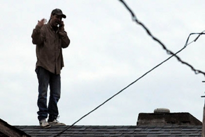 The man talks on his cellphone while standing on the roof of buildings between 54th and 55th streets in Lawrenceville.