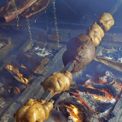 Chickens and lamb rotate over the pit in the smokehouse.