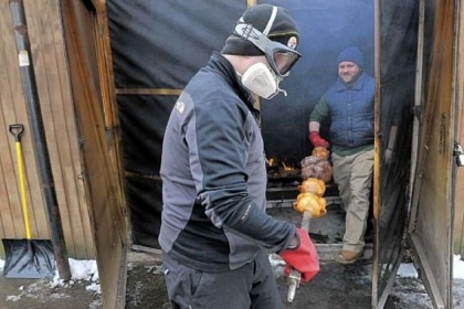 Kelly Patton, left, and Jared Lordon, carry chickens and lamb out of the smokehouse on their way to the carving table for a gathering  of lucky friends.