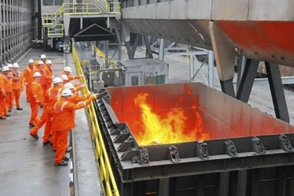 Officials gather to throw silver dollars into a carload of flaming coke fresh from the newly commissioned battery coke ovens following a ceremony at U.S. Steel's Clairton Plant. Casting silver dollars into faming coke is a long-held industry tradition when a coke oven battery is put into service.