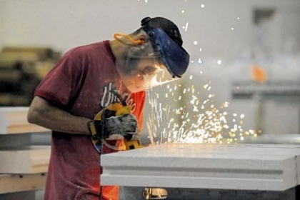 Tony Carper grinds the edges of a steel-reinforced thermal building panel after it was cut for a customer order at Syntheon's Leetsdale facility. The former Nova Chemicals company makes cast panels and concrete additives using polystyrene.