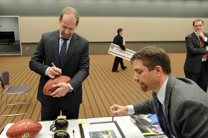 Former Steelers Coach Bill Cowher signs a football to be auctioned off for charity.