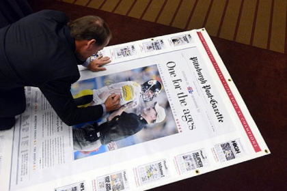 Former Steelers Coach Bill Cowher signs a large replica of the Post-Gazette edition of his Super Bowl victory to be auctioned off for charity.