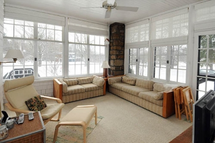 An enclosed sunporch offers a view of the fine landscaping surrounding the home.