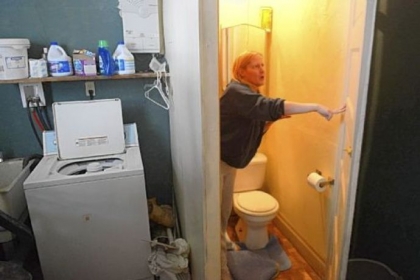 Donna Goldinger points out some of the problems in her Carrick house. She has reported some of them to the Health Department, which found raw sewage flowing into a crawl space, a lack of smoke detectors and other violations. Here, Ms. Goldinger stands near the basement toilet, where the floor, now covered by a board, has collapsed.