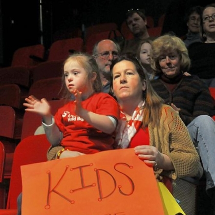 Jan Galbreath holds her daughter Cayla, 7, a first-grader at Northgate Bellevue, as they listen to singer Anne Feeney at the education rally in the Kelly Strayhorn Theater.