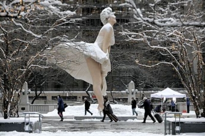 Morning commuters walk by the snow-covered 26-foot-tall sculpture of Marilyn Monroe, by Seward Johnson, on Michigan Avenue in downtown Chicago.