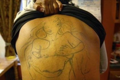 Single mother Marcy Perrin shows her tattoo, which she says symbolizes everything that being single parent is all about.  The woman in the tattoo has two faces - a happy face which she shows her children and a scared, stressed face which she hides.