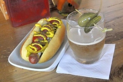 A Chicago Impostor on potato roll sits alongside the Holy Cow cocktail, which sports a caper berry (left on spear) and a cornichon at Franktuary.