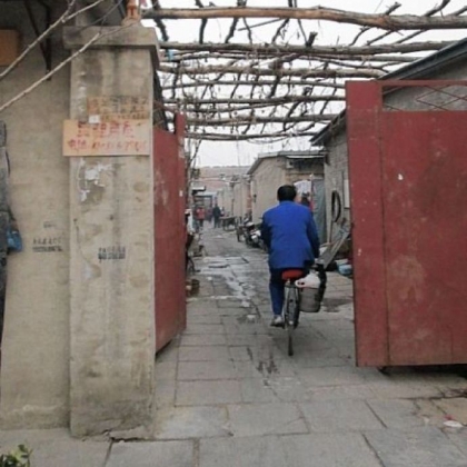 A man bicycles down an alley in a migrant neighborhood about an hour's drive from central Beijing. Families stay in meager dwellings until their jobs in the city, as hotel maids or street sweepers, can buy them better places to live.