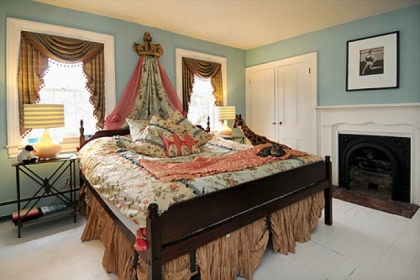 One of the upstairs bedrooms features a fireplace and tall windows.