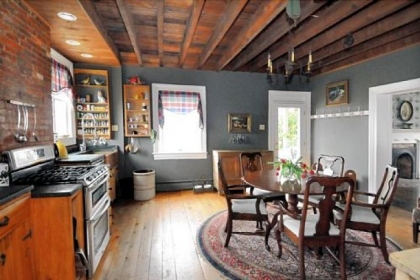 The kitchen has exposed beams and a large copper sink with a gooseneck Kohler faucet.
