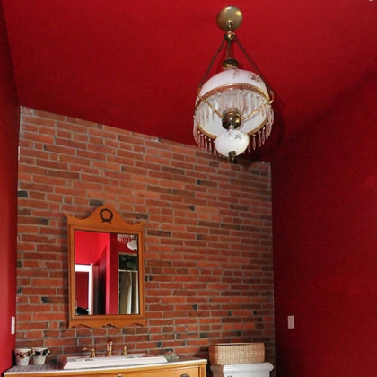 The master bathroom includes exposed brick wall, a vintage dresser converted to a vanity, an oversized shower and onyx floors.