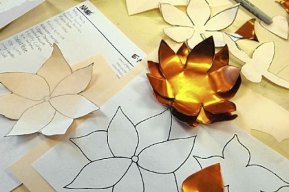Paper patterns are used to create flowers from copper.