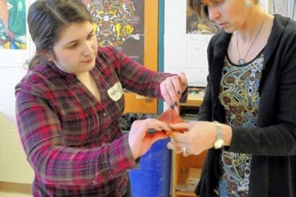 Artist Jan Loney, right, works with student Natalie Kindler to fold the copper sheeting into the shape of a flower.