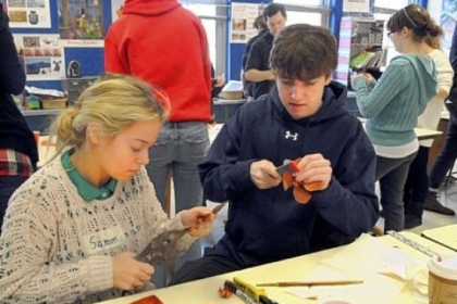 Students Samm Ballengee, left, and Patrick Burnette fashion flower elements from copper sheets.