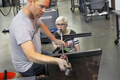 Dana Laskowski, a teaching assistant at the Pittsburgh Glass Center who began taking classes while a student at CAPA, delivers air to the project upon which teacher Jason Forck is working.