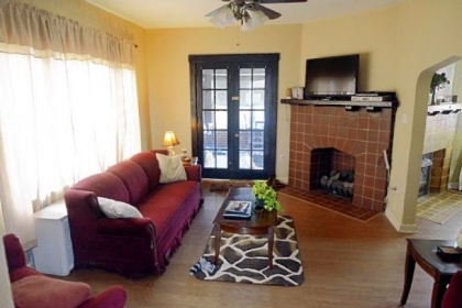The living room features an original stone gas fireplace, wood mantel and French doors.