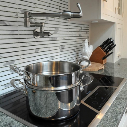 A swinging arm water faucet allows water to be added to cookware without having to carry it from the sink on the opposite side of the kitchen.