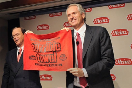 Bill Johnson, chairman, president and CEO of H.J. Heinz Co., presents a Heinz red Terrible Towel to Alex Behring, right, managing partner at 3G Capital, during a news conference announcing Berkshire Hathaway's and 3G Capital's acquisition of Heinz.