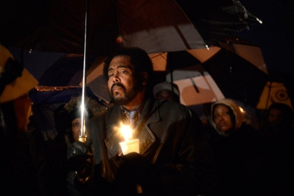 Bishop Ronald Roston (center) attends a vigil held in honor of Brian "Lil Brucey" Wright Jr., 26, Tuesday evening at the corners of Enterprise Street and Tangent Way in Larimer.  Wright's father, Brian Wright Sr., who led the service Tuesday night, called on the dozens in attendance to trust in God to heal their suffering.  Wright Sr., a pastor, also pointed out a dire need to end gun violence in Pittsburgh.