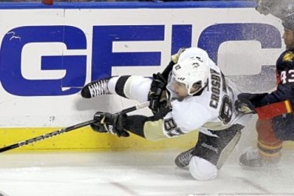 The Penguins' Sidney Crosby falls in front of Florida's Mike Weaver while trying to move the puck up the boards.
