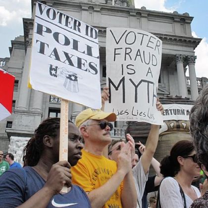 Demonstrators hold signs at a rally against the voter ID law in July in Harrisburg.