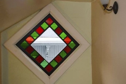 A stained-glass window on the second-floor landing casts red and green light.
