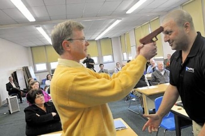 In this three-photo sequence, Sam Rosenberg, black shirt, shows North Catholic High School religion teacher Greg Evans, left, how to disarm a gun-wielding intruder at close range during a session at the Troy Hill school on Monday.