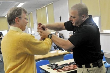In this three-photo sequence, Sam Rosenberg, black shirt, shows North Catholic High School religion teacher Greg Evans, left, how to disarm a gun-wielding intruder at close range during a session at the Troy Hill school on Monday.