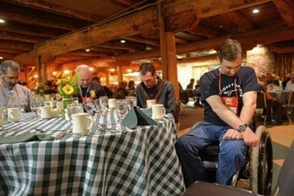 Erik Burmeister, right, a former Army National Guard member from Williamsport, Pa., bows his head for a prayer during a Wounded Warriors retreat banquet dinner held at Seven Springs Mountain Resort.