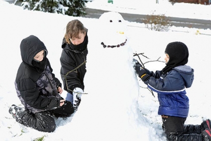 Tiffany Grimes of Franklin Park, makes a snowman with her sons, Luke, left, 8, and Hunter, 5, in their front yard today.