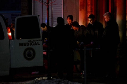 Allegheny County Medical Examiners pull a gurney out of their truck to transport a 24-year-old homicide victim from the apartment building on Penn Avenue, where he was found shot.