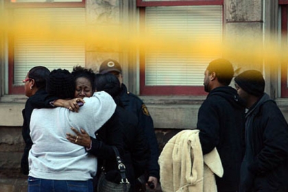A group of people comfort each other near the Friendship apartment building where a 24-year-old man was found shot to death.