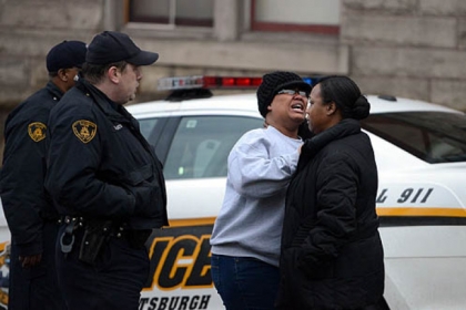 Two women embrace each other near an apartment building where a 24-year-old man was found shot to death.