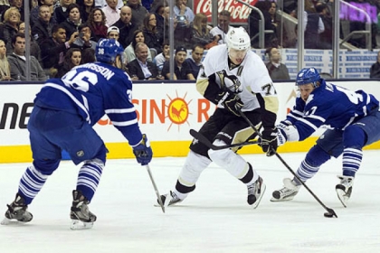 The Penguins' Evgeni Malkin takes the puck between the Toronto Maple Leafs' Carl Gunnarsson, left, and Leo Komarov.